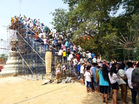 Description: People form a bucket brigade to bring cement and precious items to be put on top of the new Buddha statue in Rayong.